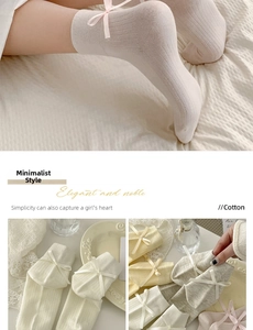 Dettaglio di calzini in cotone a coste con delicati fiocchi di nastro color crema e beige
