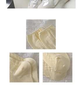 Macro detail of cream knit socks with cable pattern texture and ribbed cuffs