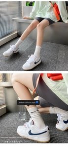 Close-up of white cotton crew socks with text detail paired with blue logo sneakers