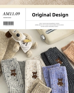 Détail de chaussettes en laine tricotée avec broderie d'ours et texture côtelée chic
