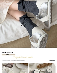Detail of dark gray cotton ribbed socks with black bow accent and silver sneakers