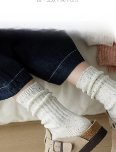 Close-up of cream wool blend socks with colorful speckles and vertical rib texture
