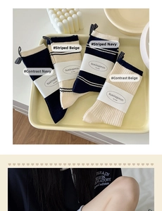 Detail of college style striped cotton crew socks in navy and beige with brand tags