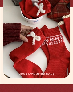 Close-up of red festive knit socks featuring white plush bows and snowflake patterns