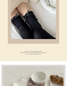 Detail of black knit mid-calf socks with vertical ribs and elegant satin bow accents