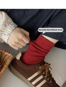 Détail de chaussettes plissées en maille bordeaux portées avec baskets marron