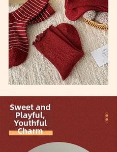 Detail of red wool socks featuring white stripes and ruffled edges for holiday warmth