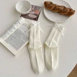 Elegant cream white ribbed crew socks with satin bow detail on a rustic French table