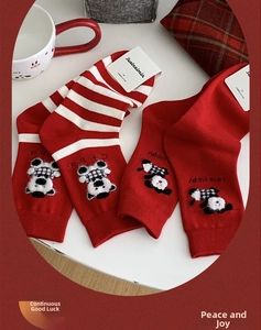 Detailed close-up of red festive socks with cute animal embroidery and combed cotton label