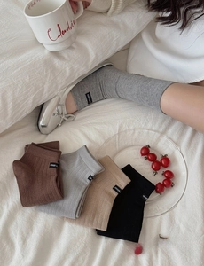 Detail of knitted mid-calf socks in brown, grey, beige and black with vertical rib texture