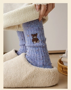 Détail d'une chaussette en laine bleue tricotée avec broderie ours et chaussons doux