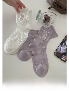 Close-up of cute bear embroidery and 3D jacquard texture on white and purple mid-calf socks