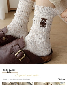 Détail de chaussettes en laine crème avec broderie ours et bords côtes en sandales