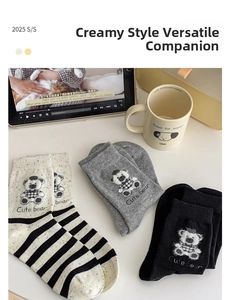 Detailed view of mid-calf socks featuring cute teddy bear embroidery in stripes, grey, and black
