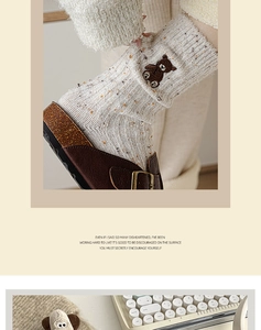 Détail de chaussettes en laine blanc cassé avec broderie ours et texture chinée
