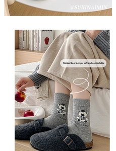 Detail of grey socks featuring flocked bear pattern and Cute Bear text in a home setting