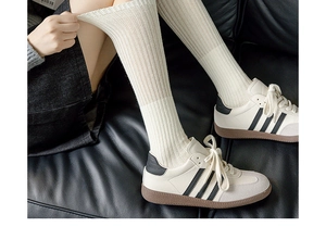 Detailed view of ribbed knit cream knee-high socks showing texture and elasticity