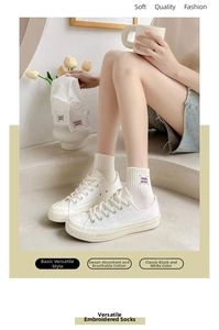 Dettaglio di calze di cotone bianco con ricamo rosa 'made good' e coste in stile atletico