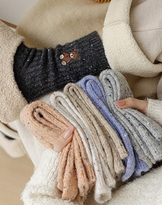 Détail de chaussettes thermiques en laine avec broderie ours et taches colorées