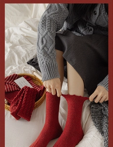 Detail of red wool socks with cable knit patterns and elastic ruffle cuffs for women