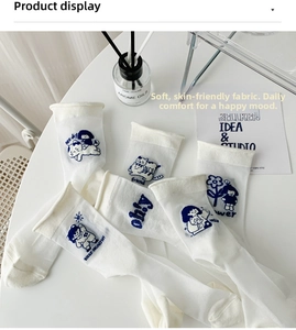 Detail of white cotton socks featuring blue cartoon embroidery and Japanese style roll edge