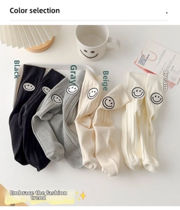 Close-up of four-pack crew socks in neutral tones with minimalist smile embroidery