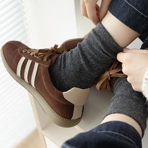 Baskets en daim marron avec rayures blanches portées avec des chaussettes en laine