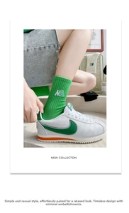 Gros plan de chaussettes en coton côtelé vert avec broderie blanche de la lettre NA au bord