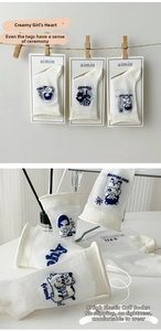 Detailed view of cream mid-calf socks with cute cartoon embroidery and rolled cuffs