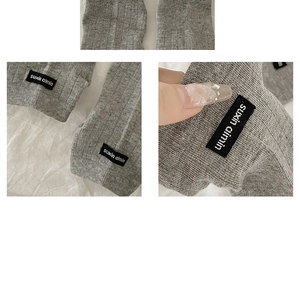 Detailed view of grey ribbed knit texture with a branded woven label on the edge