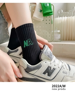 Gros plan sur des chaussettes en coton côtelé noir avec broderie verte NA sur le côté