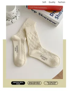 Dettaglio di calze in cotone beige con trama a rombi e logo del marchio sulla suola
