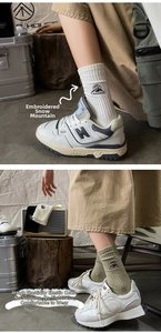 Detail of embroidered mountain peaks and Camping text on cotton crew socks in nature