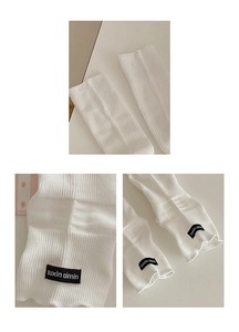Close-up of white ribbed knit leg warmers with ruffle edge and black woven label detail