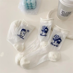 White Japanese crew socks with blue cartoon patterns and stylish rolled edges for women