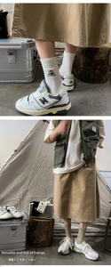 Close-up of white ribbed socks with mountain embroidery and vintage camping sneakers