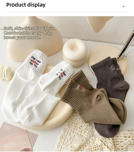 Close-up of three mid-calf socks in beige and grey with embroidered 'The best wishes' text