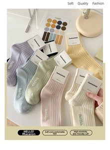 Gros plan de chaussettes en coton peigné pastel avec tricot vertical et broderie hello