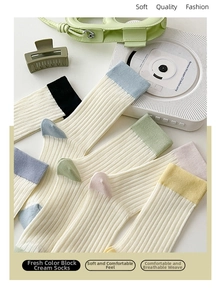 Detail of colorful rib-knit crew socks in cream white with vibrant contrast cuffs
