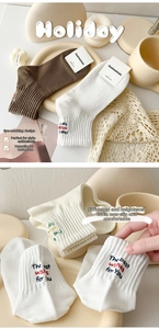Detail of combed cotton mid-calf socks with letter embroidery in white and brown