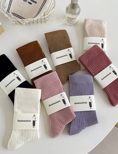 Flat lay of colorful ribbed knit crew socks in earth tones with minimalist packaging