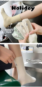 Detail of ribbed cotton mid-calf socks showing the wide cuff and slogan woven label