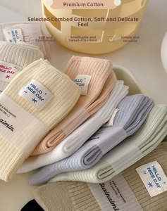 Detailed view of colorful ribbed cotton socks with white logo tags and paper packaging