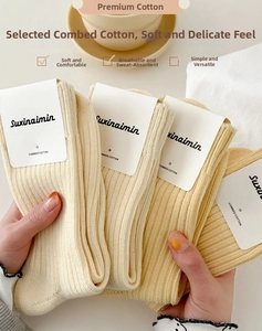 Detail of soft combed cotton ribbed socks in cream and yellow with paper packaging
