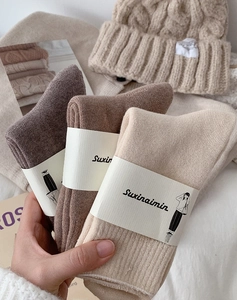 Dettaglio di calze spesse in maglia nei colori marrone, cammello e beige con etichette