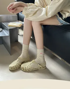 Close-up of cream woven loafers with metal buckle worn with ribbed mid-calf socks