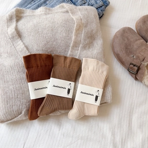 Three pairs of earth-tone cotton slouch socks with vertical rib knit texture and labels