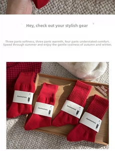 Detail of red festive cotton socks with ribbed cuffs and branded packaging on wood tray