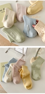 Détail de chaussettes en coton côtelé avec broderie hello aux couleurs macaron
