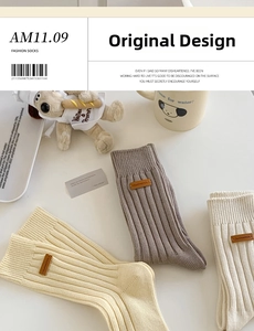 Detail of ribbed cotton mid-calf socks with brown leather label in beige and taupe